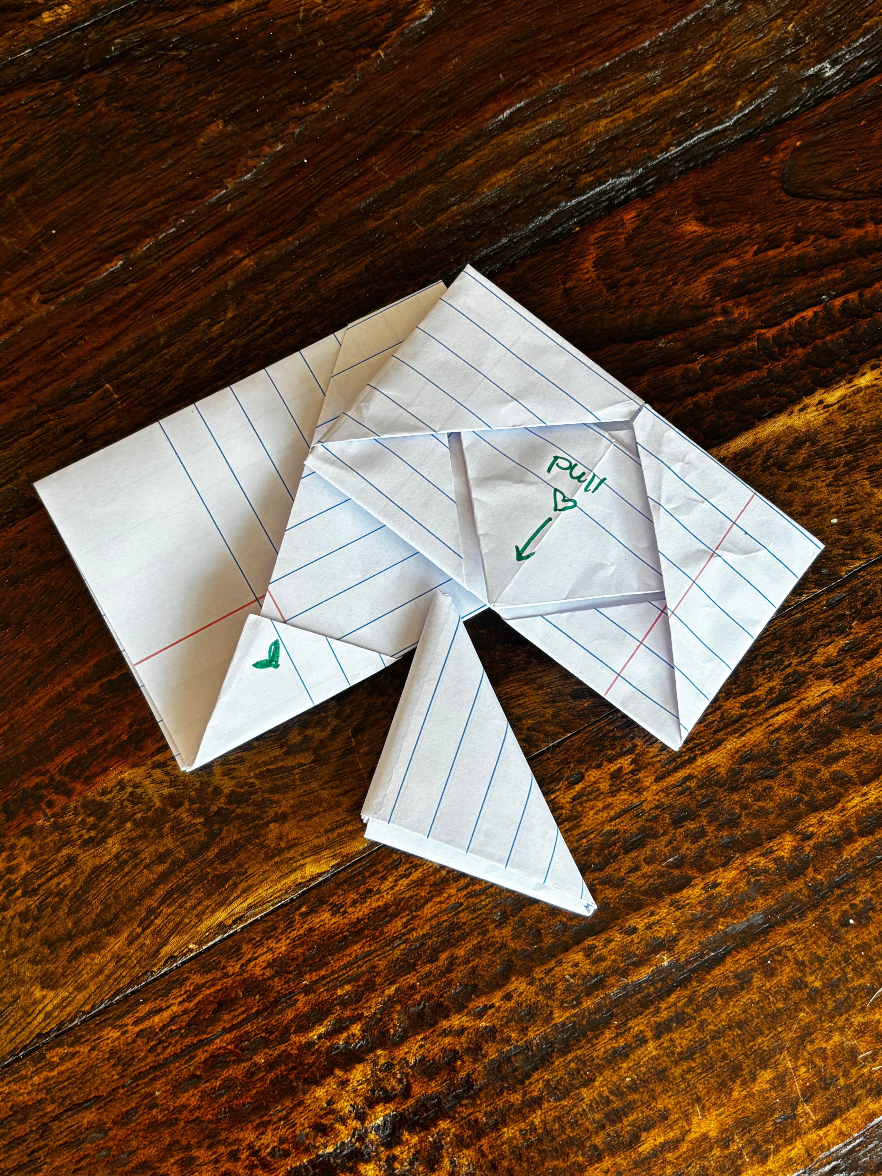 Folded handwritten school notes scattered on a wooden table.